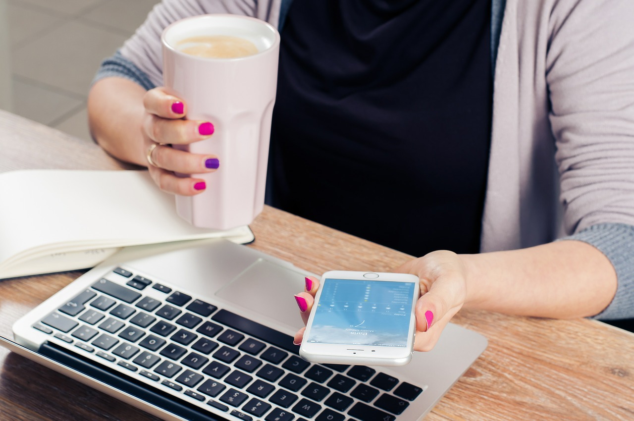 Woman holding a mobile phone on the left and coffee on the right